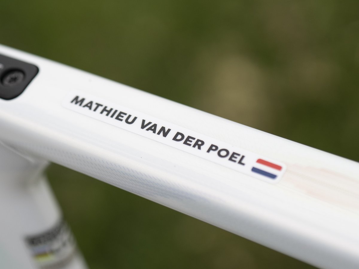 Naamsticker van Mathieu van der Poel met Nederlandse vlag op de bovenbuis van zijn witte fiets