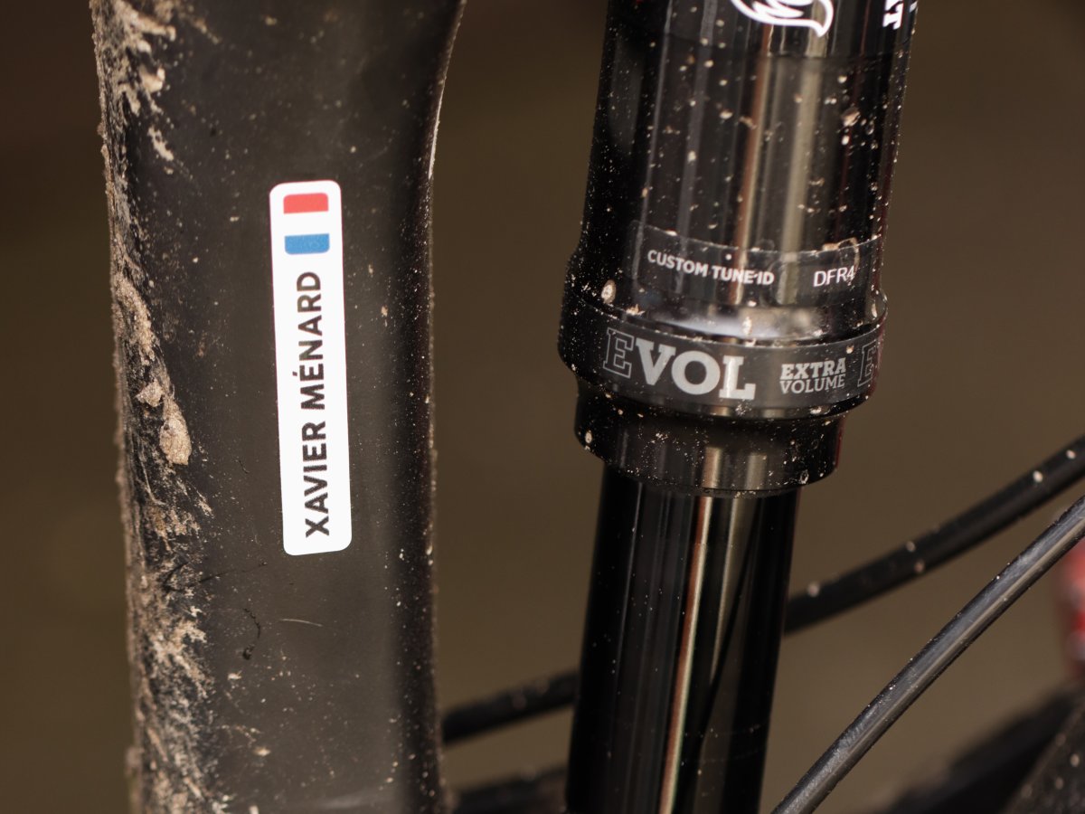 Witte naamsticker met Franse vlag op de zitbuis van een modderige mountainbike